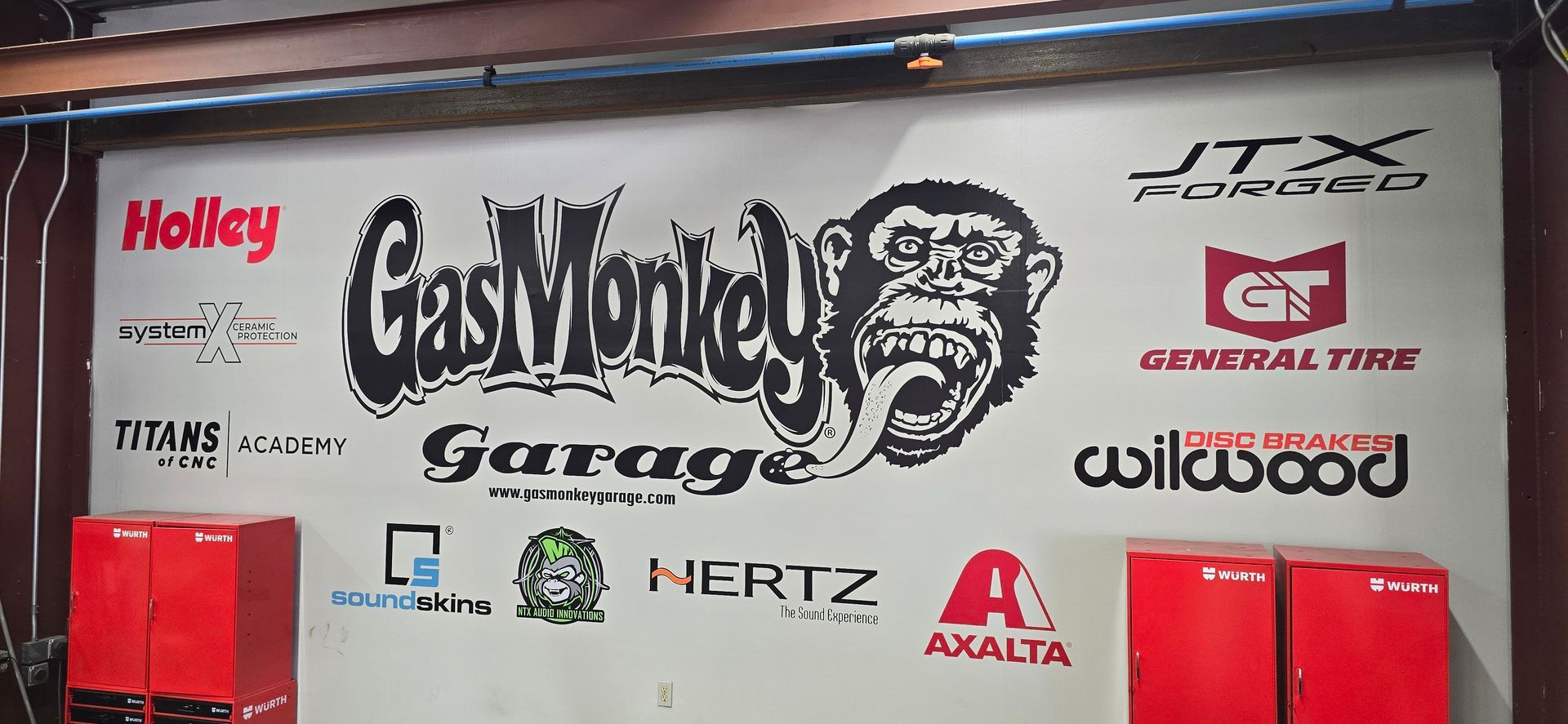 A gas monkey garage wall with various logos on it