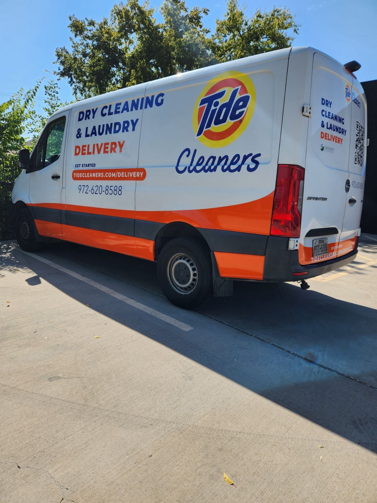 A white and orange tide cleaners van is parked on the side of the road.