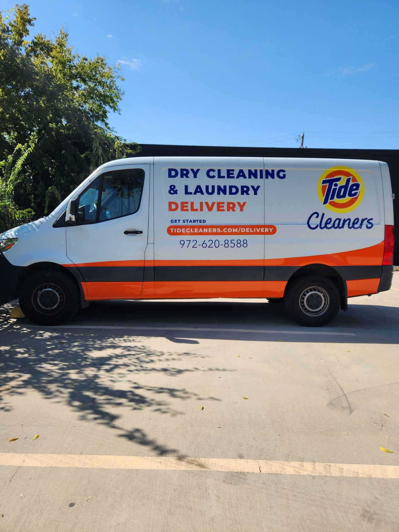 A dry cleaning and laundry delivery van is parked in a parking lot.
