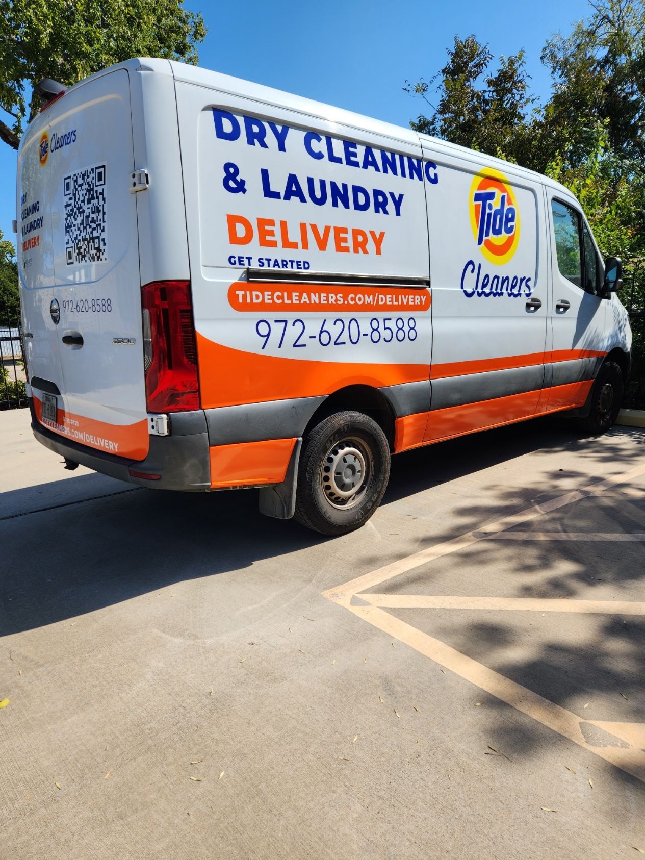 A dry cleaning and laundry delivery van is parked in a parking lot.
