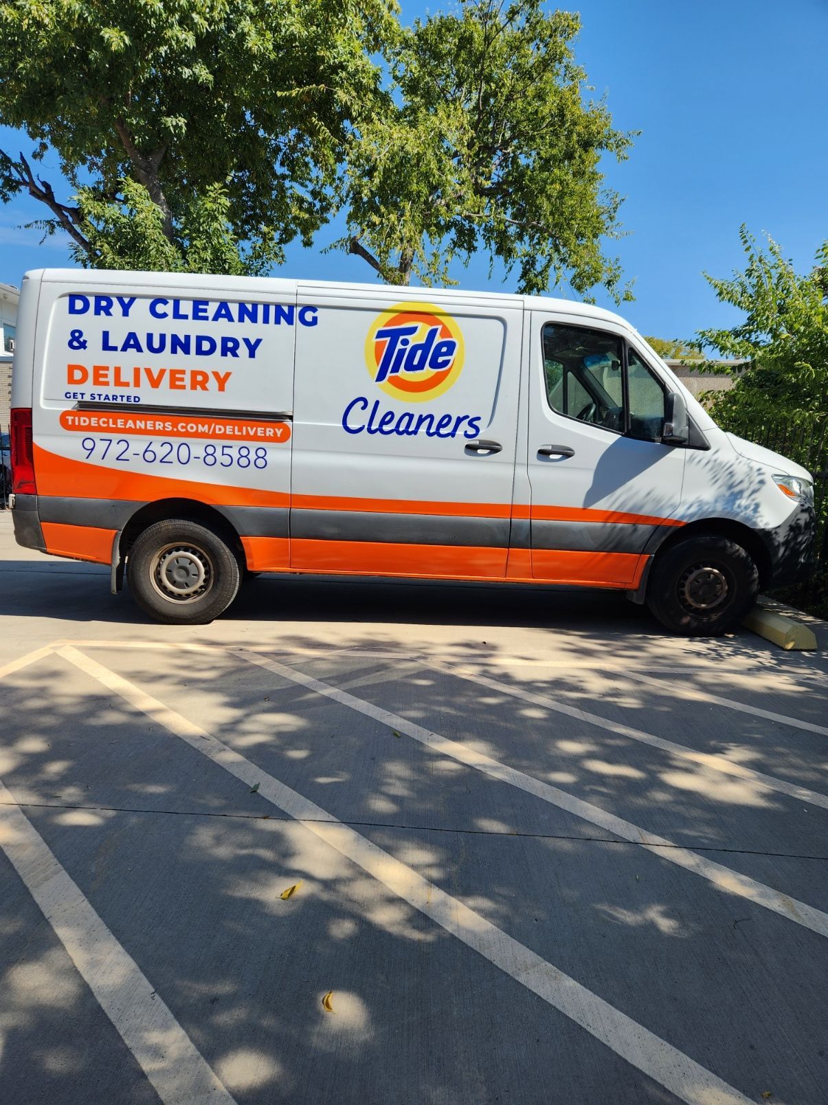A dry cleaning and laundry delivery van is parked in a parking lot.