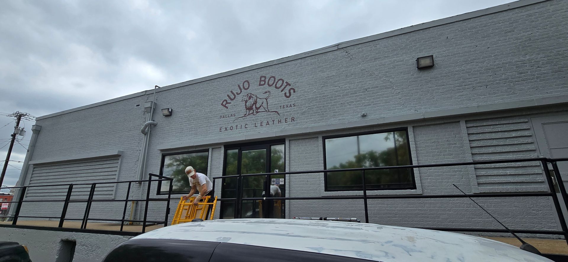 A man is standing on a ladder in front of a building.