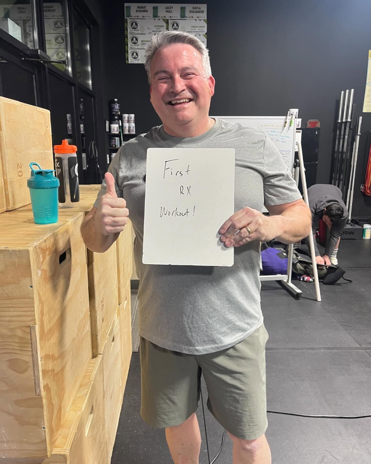 A man is giving a thumbs up while holding a piece of paper that says 