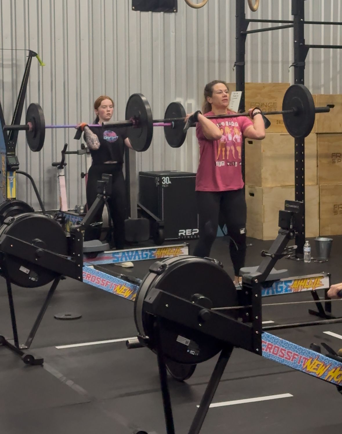 A man is lifting a barbell over his head in a gym.
