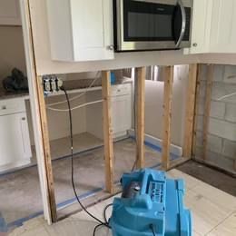 A blue vacuum cleaner is sitting in a kitchen next to a microwave.