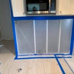 A kitchen with a microwave and a refrigerator covered in plastic.