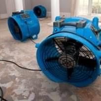 Two blue fans are sitting on the floor in a room.