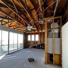 An empty room with a lot of windows and a ceiling fan.