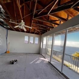 An empty room with a lot of windows and a ceiling fan.
