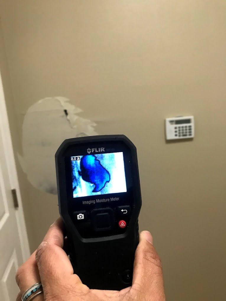 A person is holding a flir camera in front of a wall.