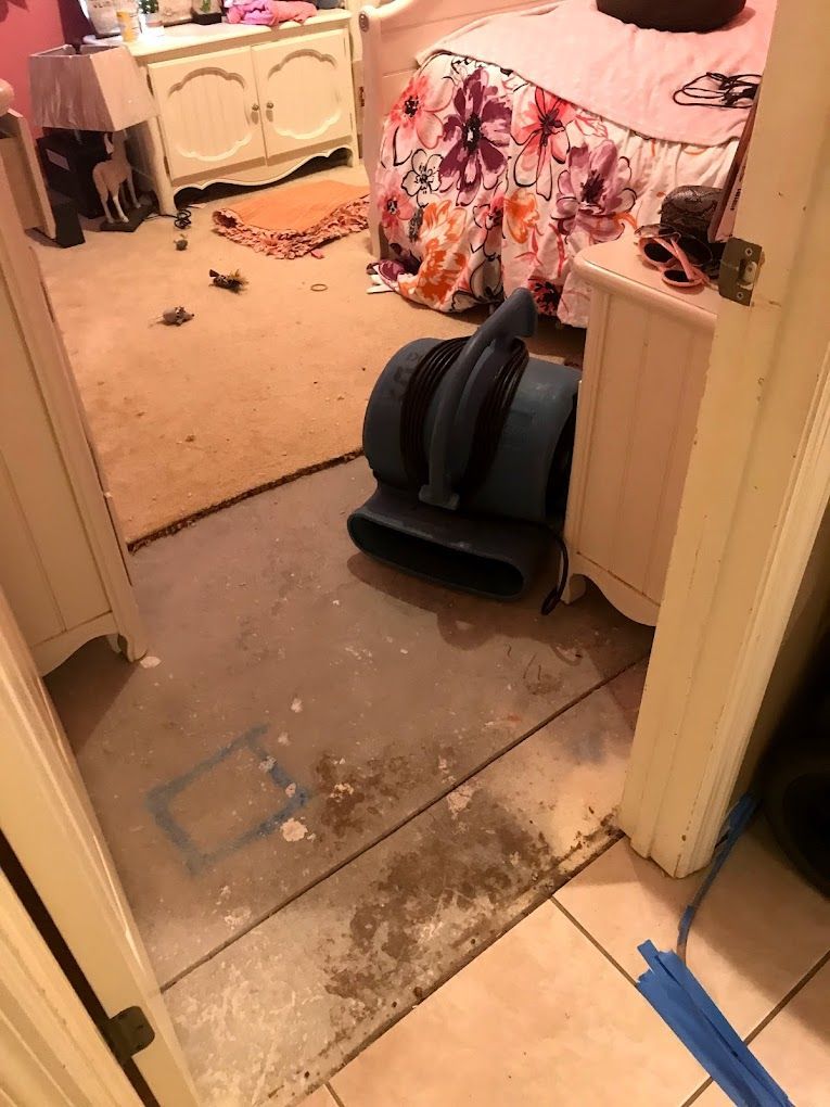 A bedroom with a bed and a fan on the floor