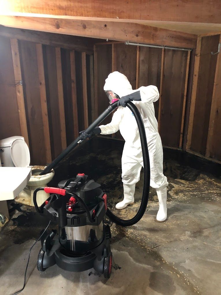 A man in a protective suit is using a vacuum cleaner in a bathroom