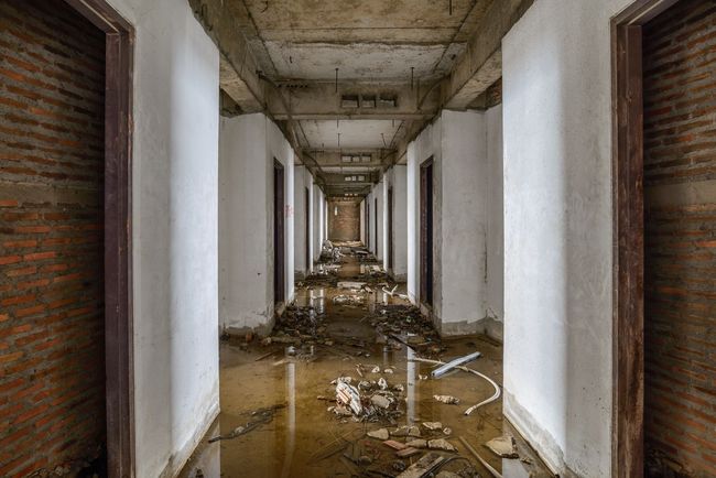 A long hallway in an abandoned building with a lot of water on the floor.