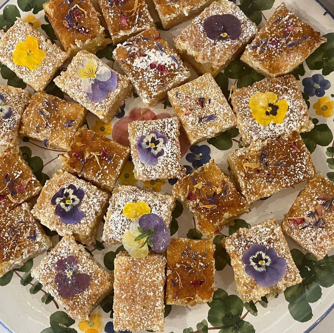 Lemon bars topped with edible flowers and powdered sugar.
