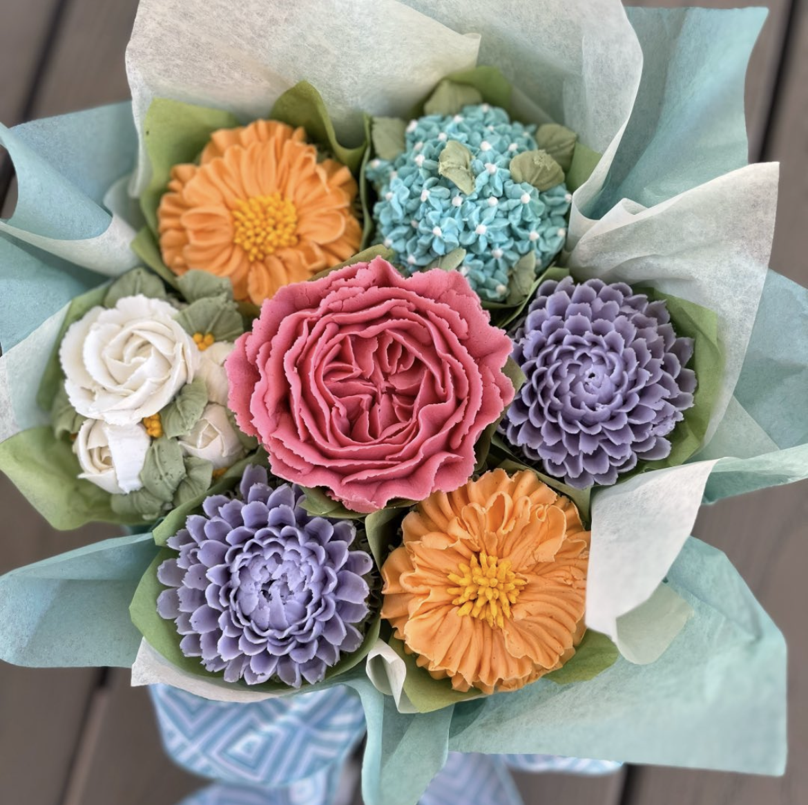 Cupcake bouquet with buttercream flowers in shades of orange, purple, pink, blue and white.