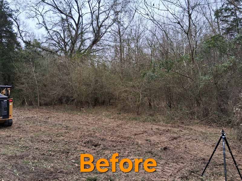 A wooded clearing with brush at the edge, a piece of heavy equipment on the left, and a tripod on the right. Labeled 