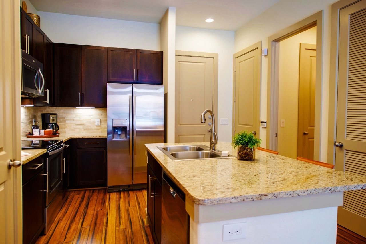 Modern apartment kitchen with granite countertops, stainless steel appliances, and island.