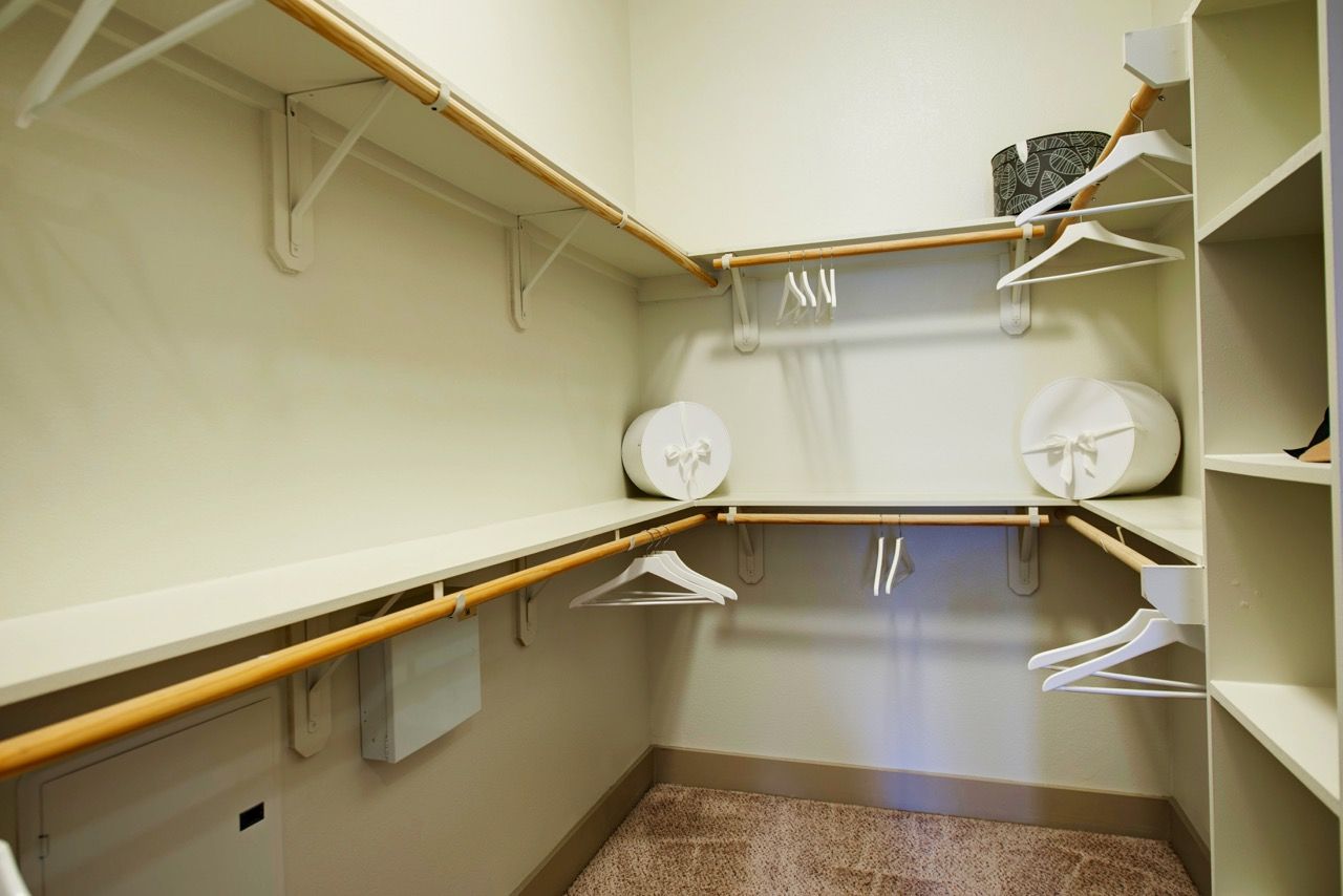 Walk-in closet with built-in shelves, rods, and white hangers.