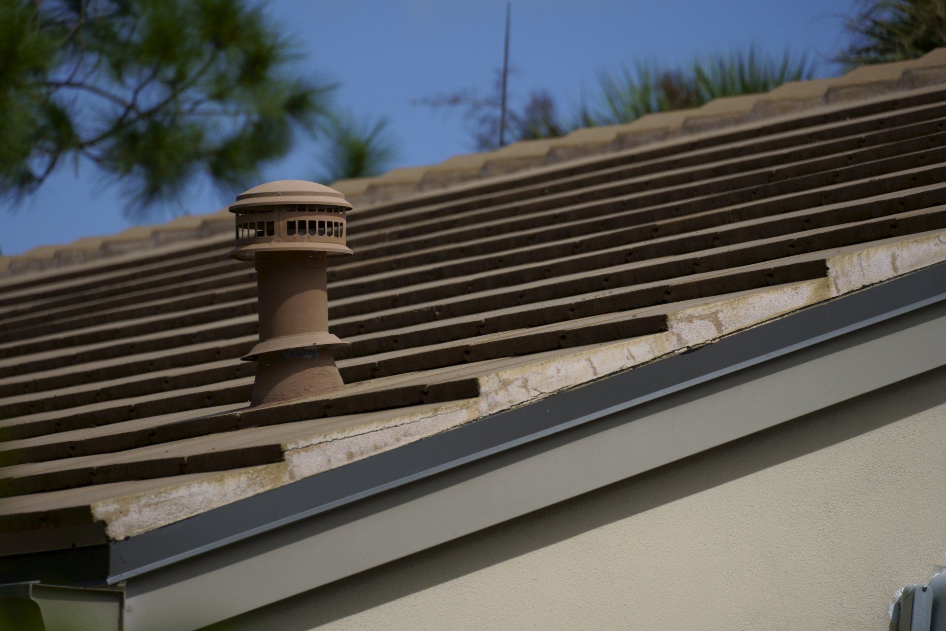 Brown tile roof with a chimney and blue sky.