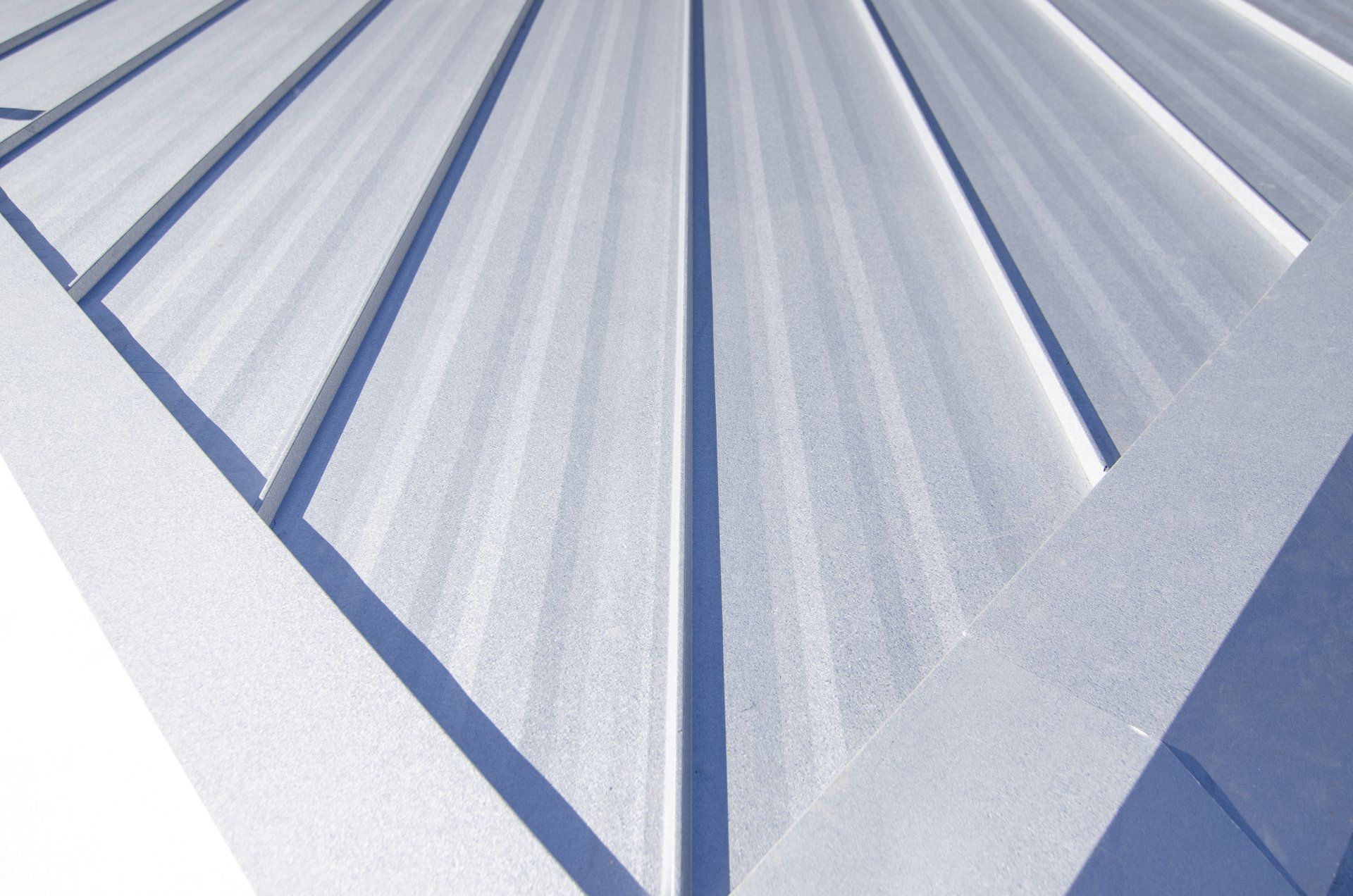 Close-up of a silver metal roof with vertical ridges and structural framing at the edges.