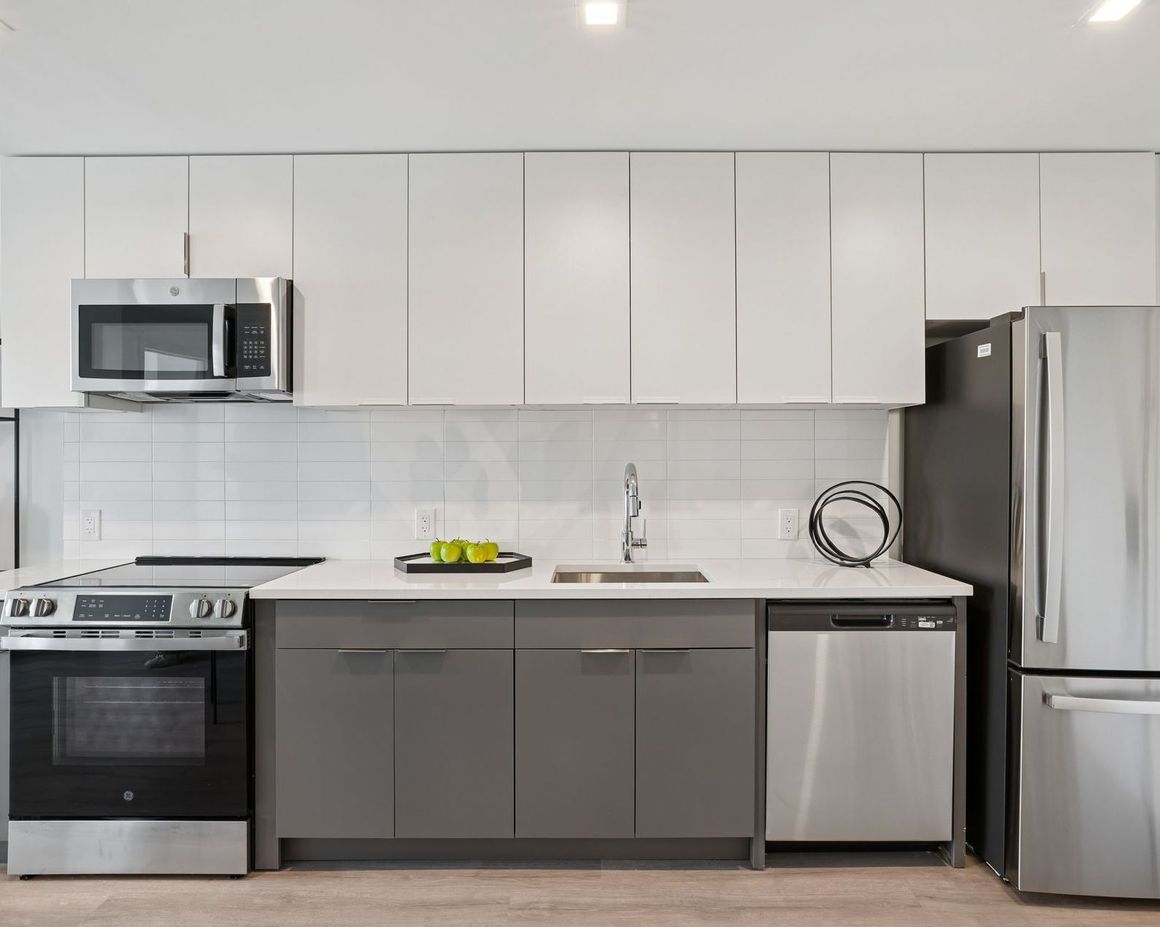 A kitchen with stainless steel appliances and gray cabinets
