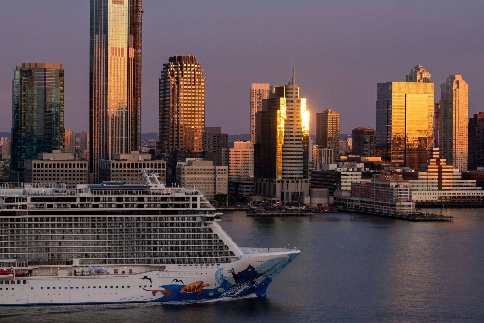 A cruise ship in the water with a city skyline in the background