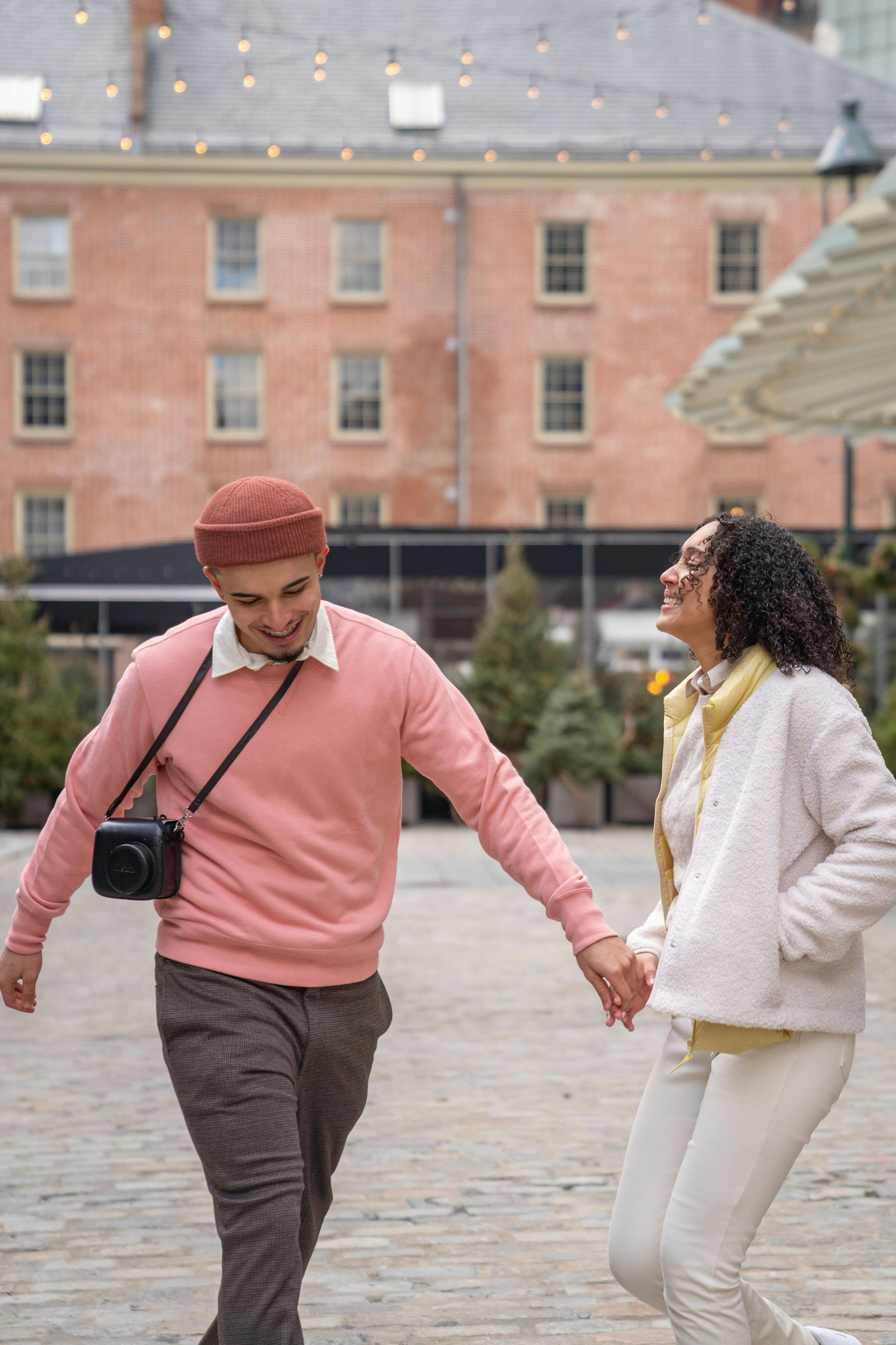 A man and a woman are holding hands while walking down a street.