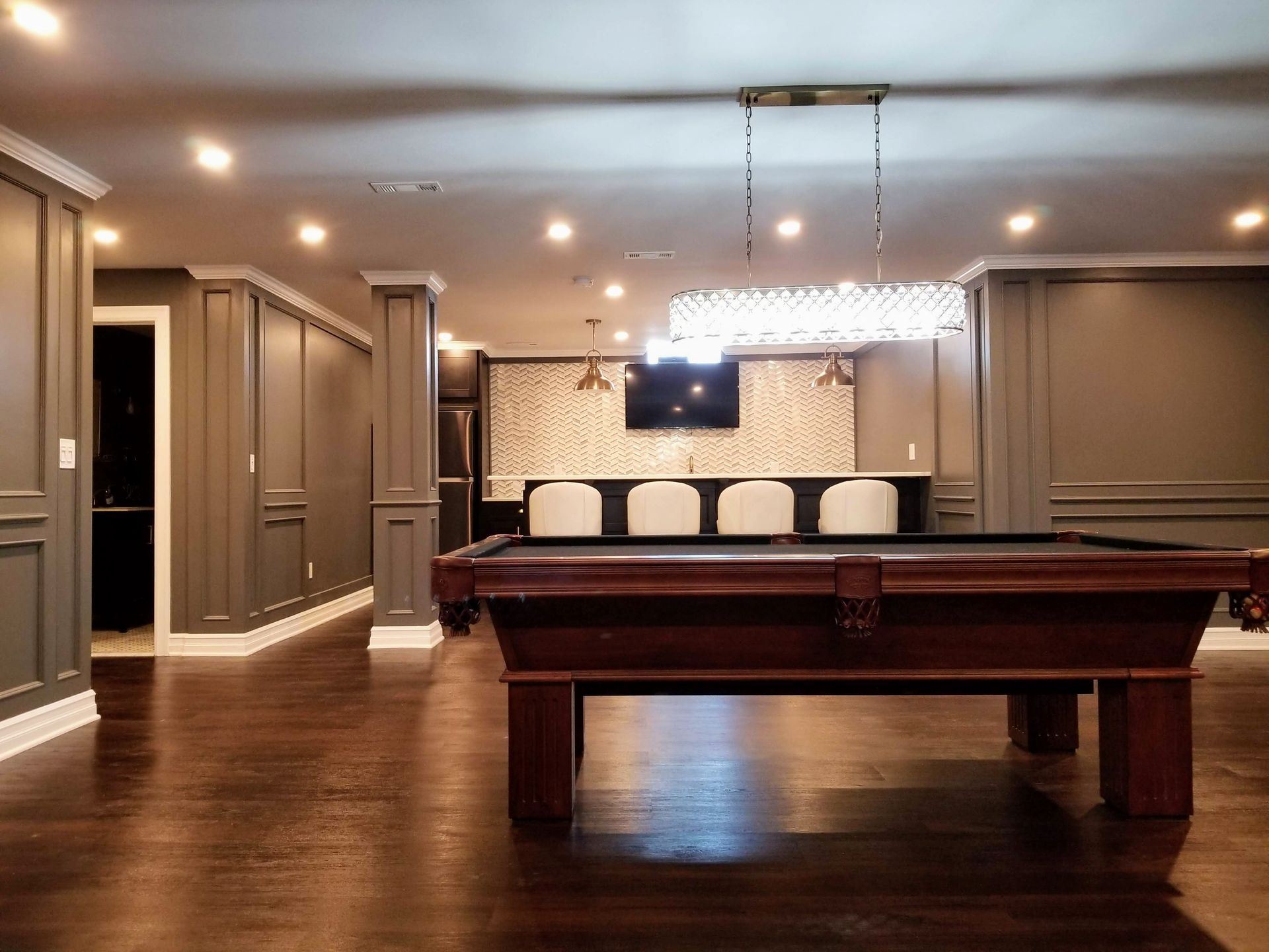 A pool table in a basement with a chandelier hanging from the ceiling