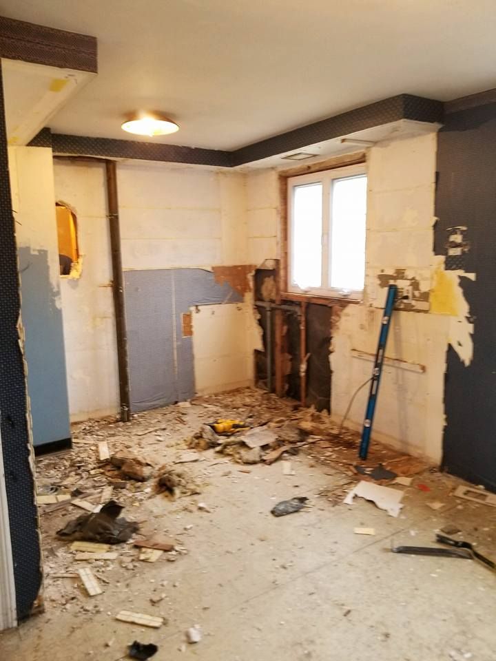 A room with a lot of trash on the floor and a window.