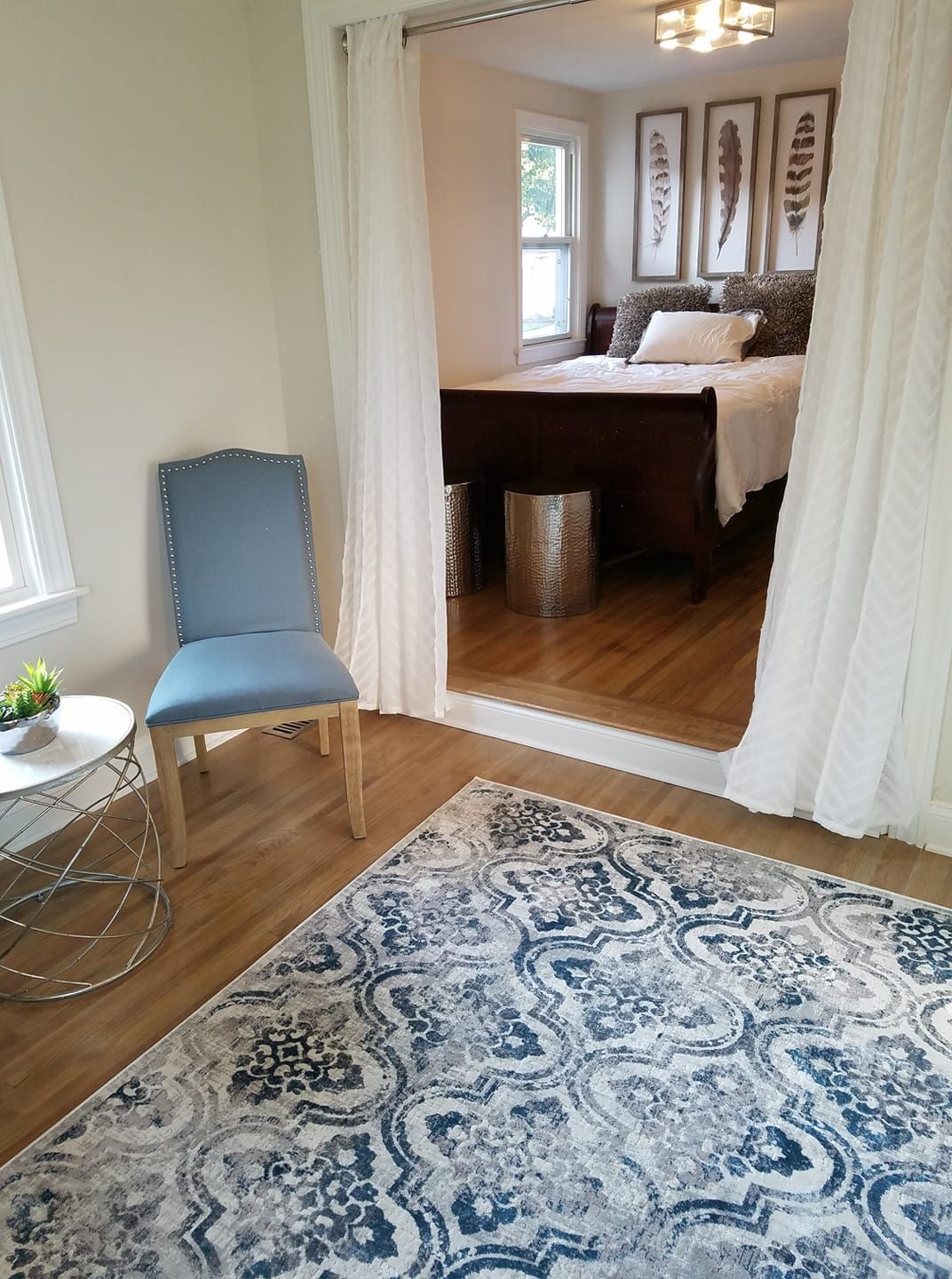 A bedroom with a bed , chair , table and rug.