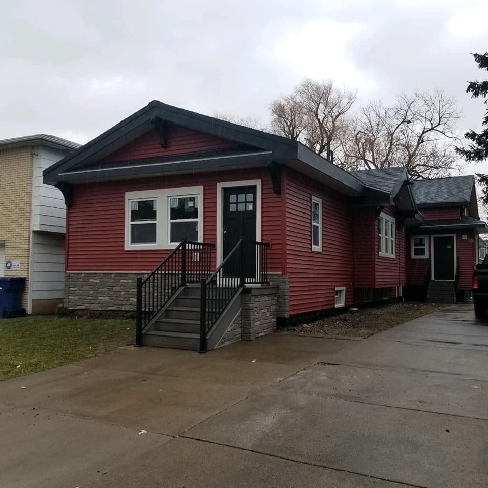 A small red house with stairs leading up to the front door