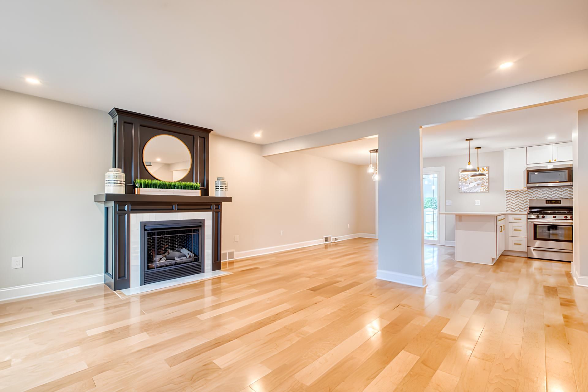 An empty living room with hardwood floors and a fireplace.