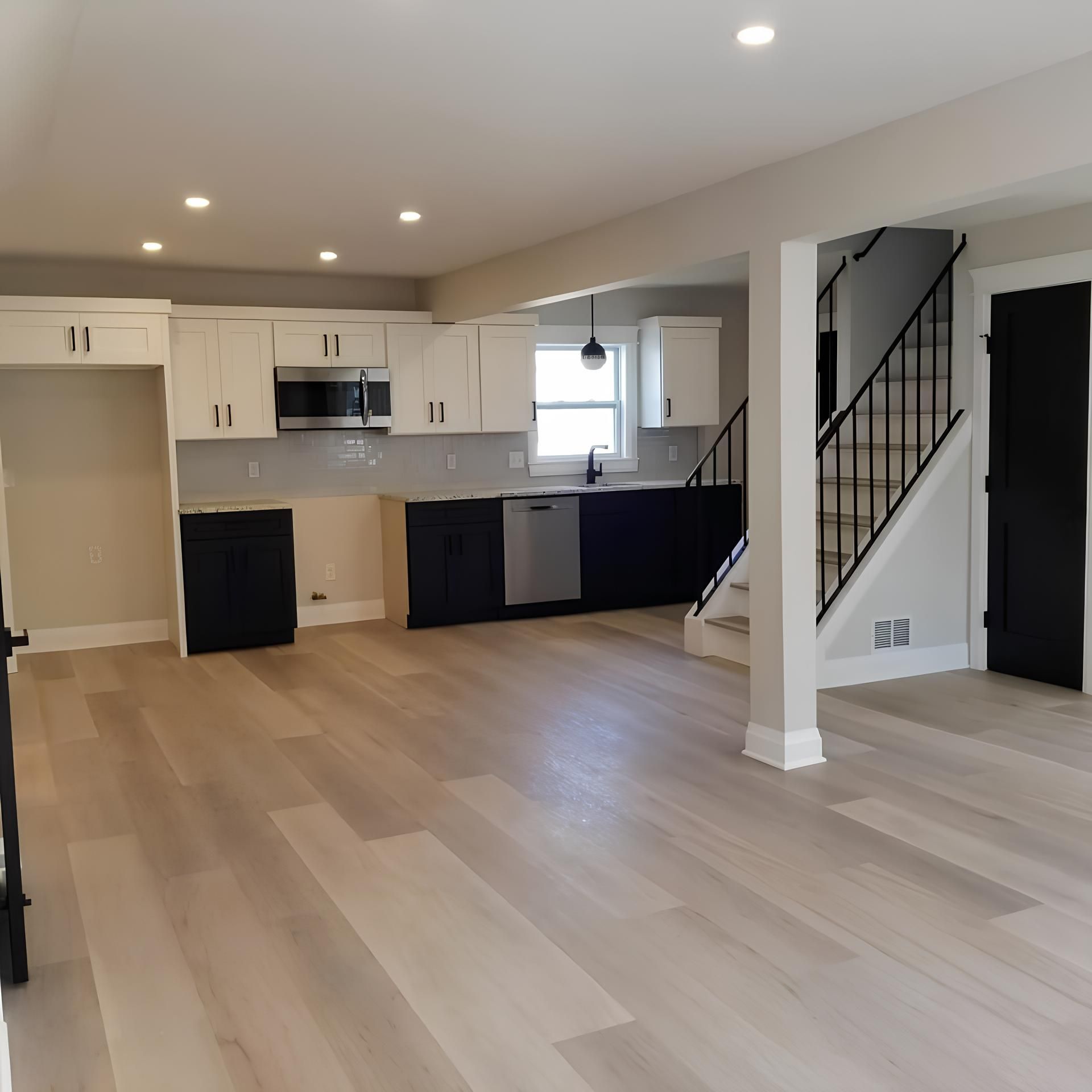 An empty kitchen with stairs leading up to the second floor
