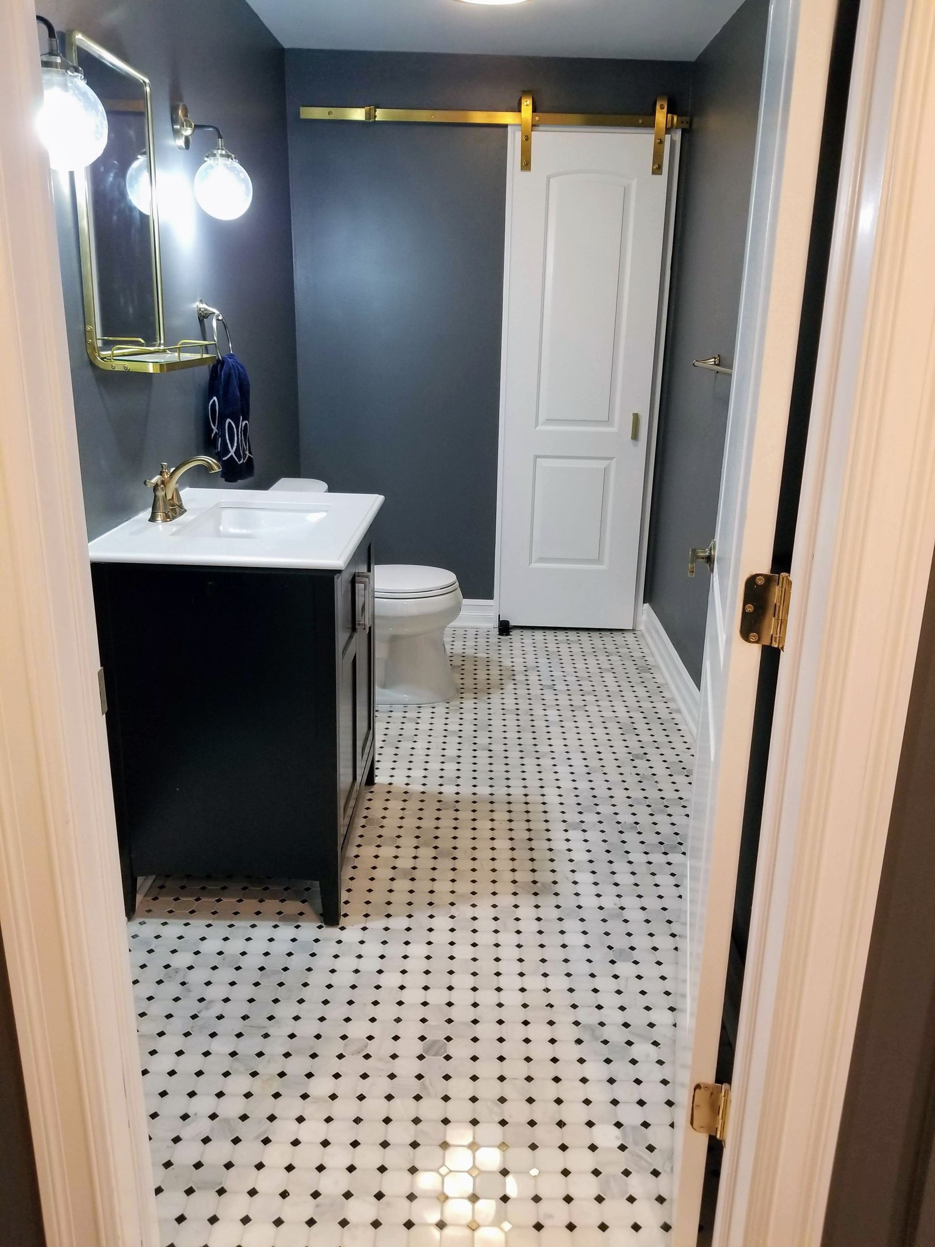 A bathroom with a sink , toilet , mirror and sliding barn door.
