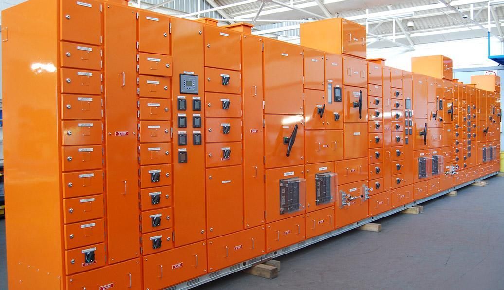 Orange electrical control panels in an industrial setting, with various switches and meters visible on their faces.