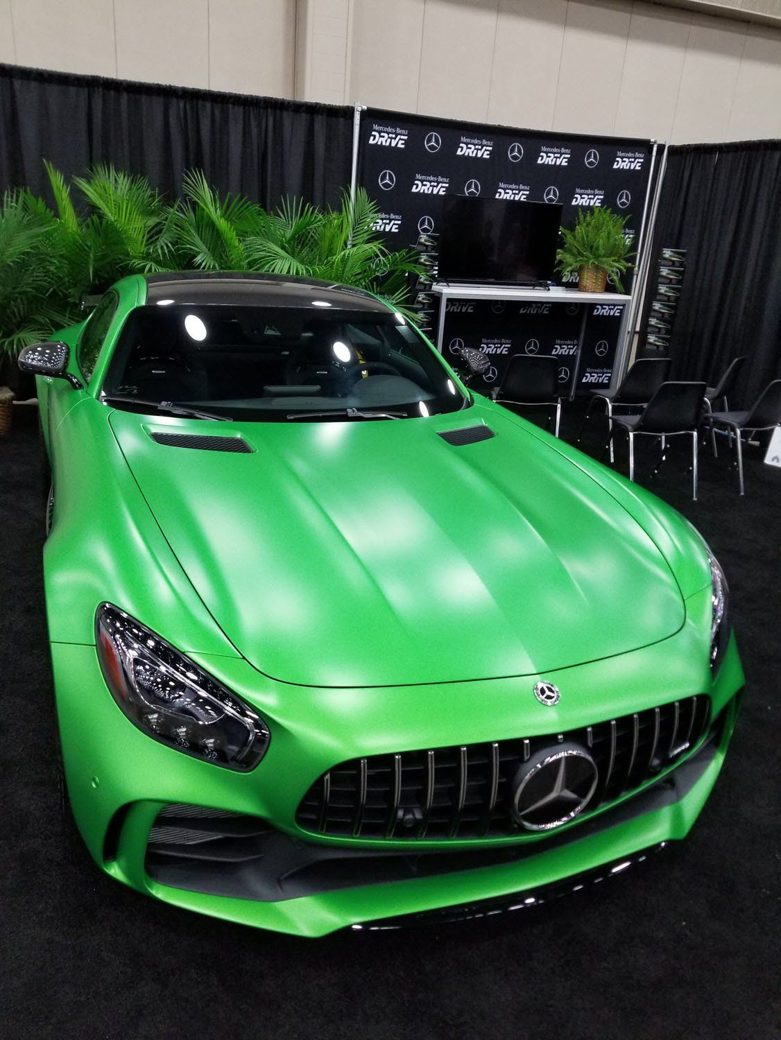 Green Mercedes-AMG GT sports car on display, with black trim and a black background.