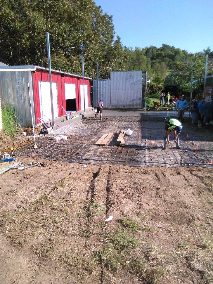 team pouring concrete on side of house