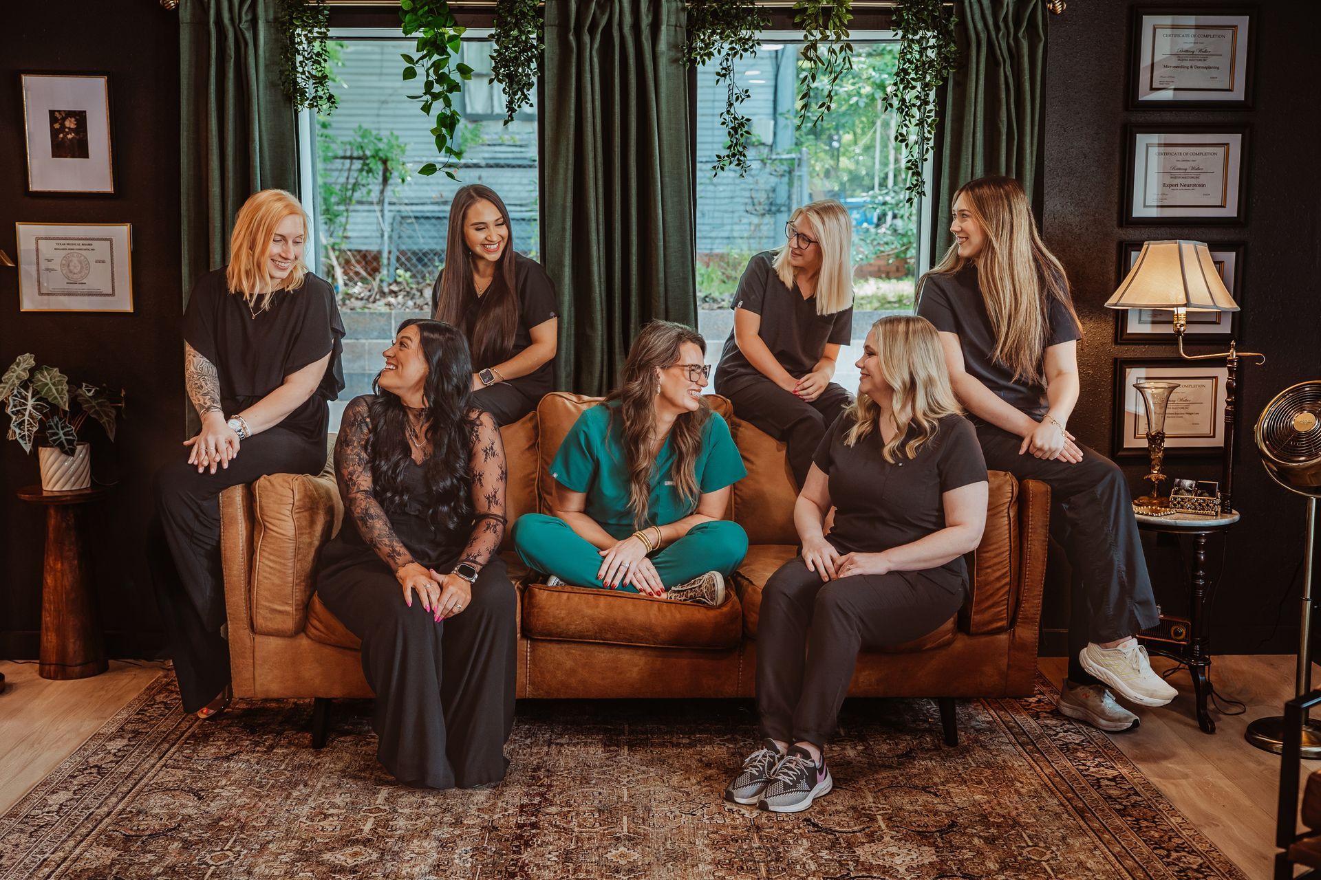 Group of women in a dark room pose on and around a brown couch.