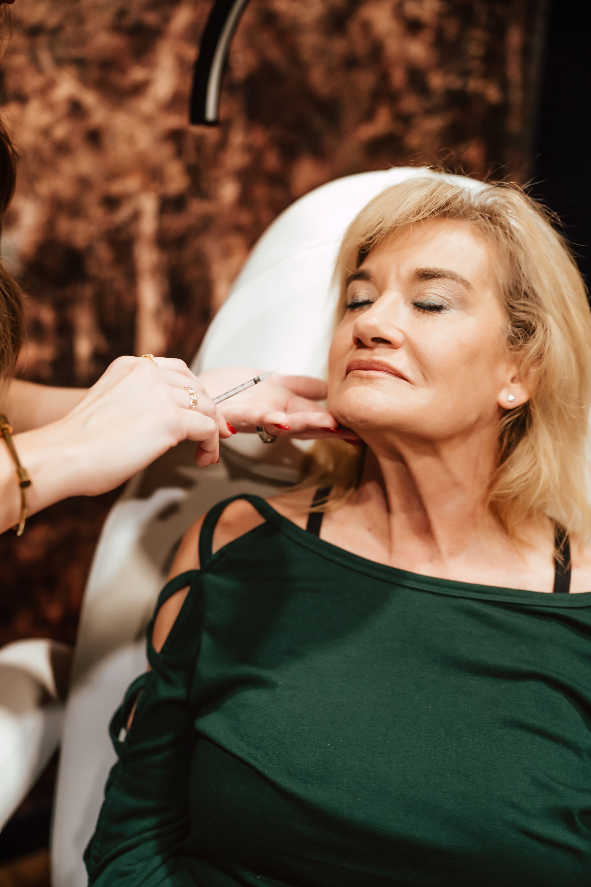 Woman receiving injection in neck; spa setting.