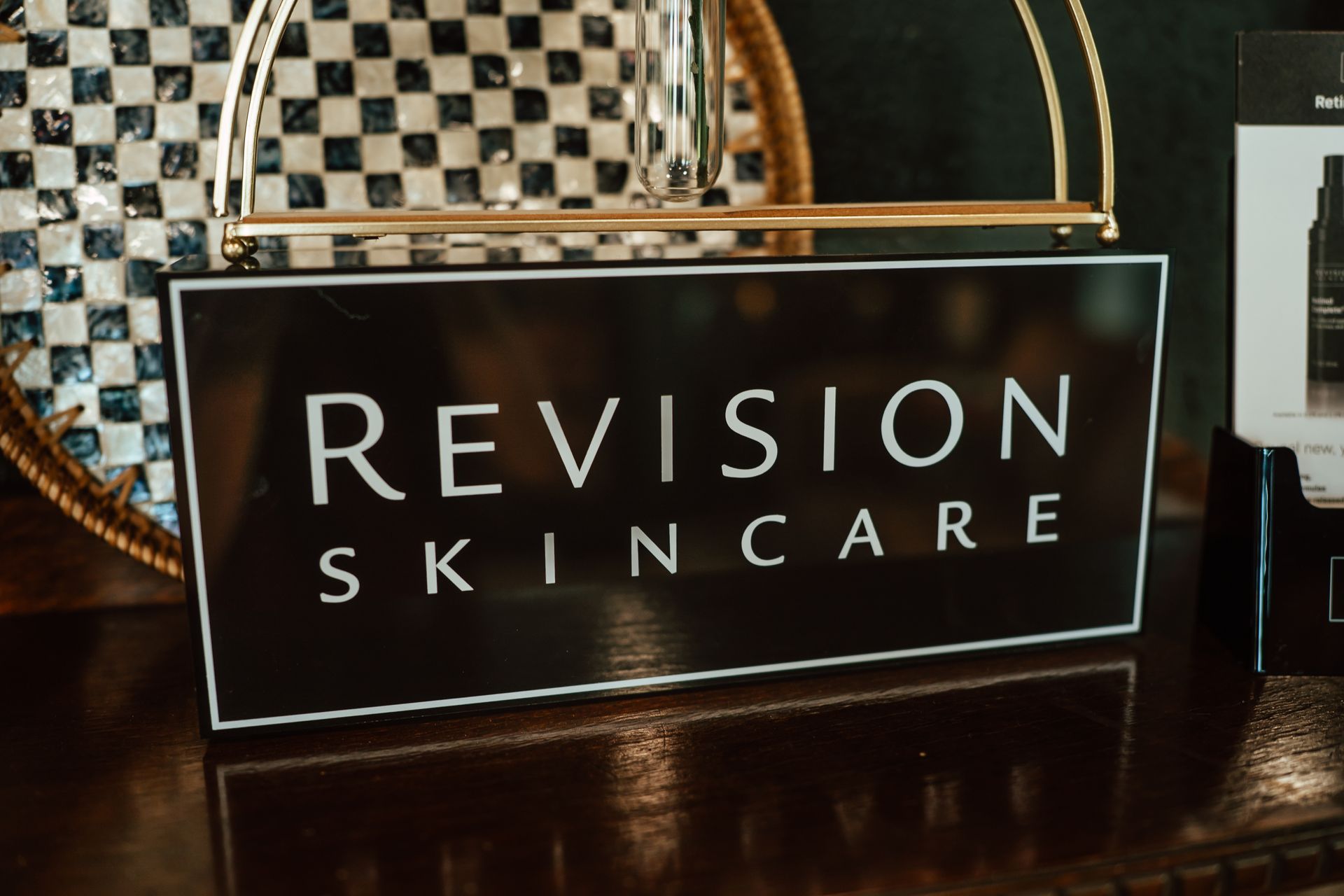 Black and white sign for Revision Skincare on a table.