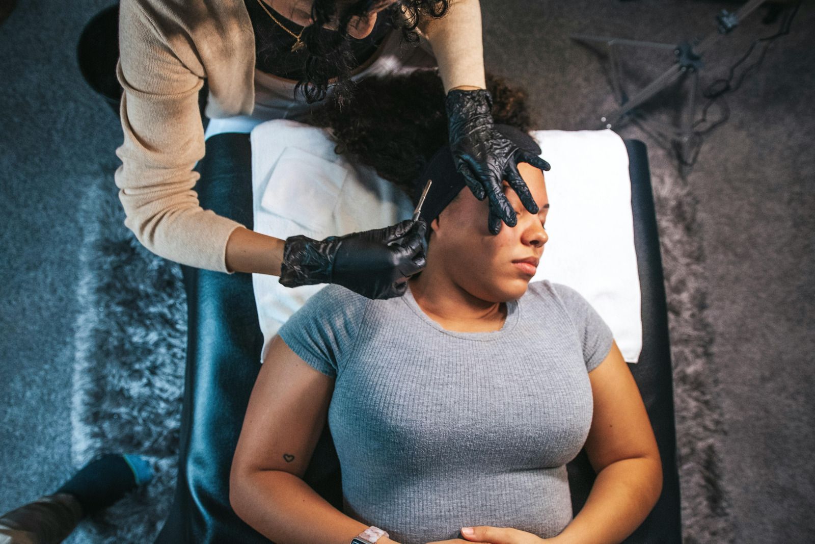 A woman is getting a tattoo on her forehead.
