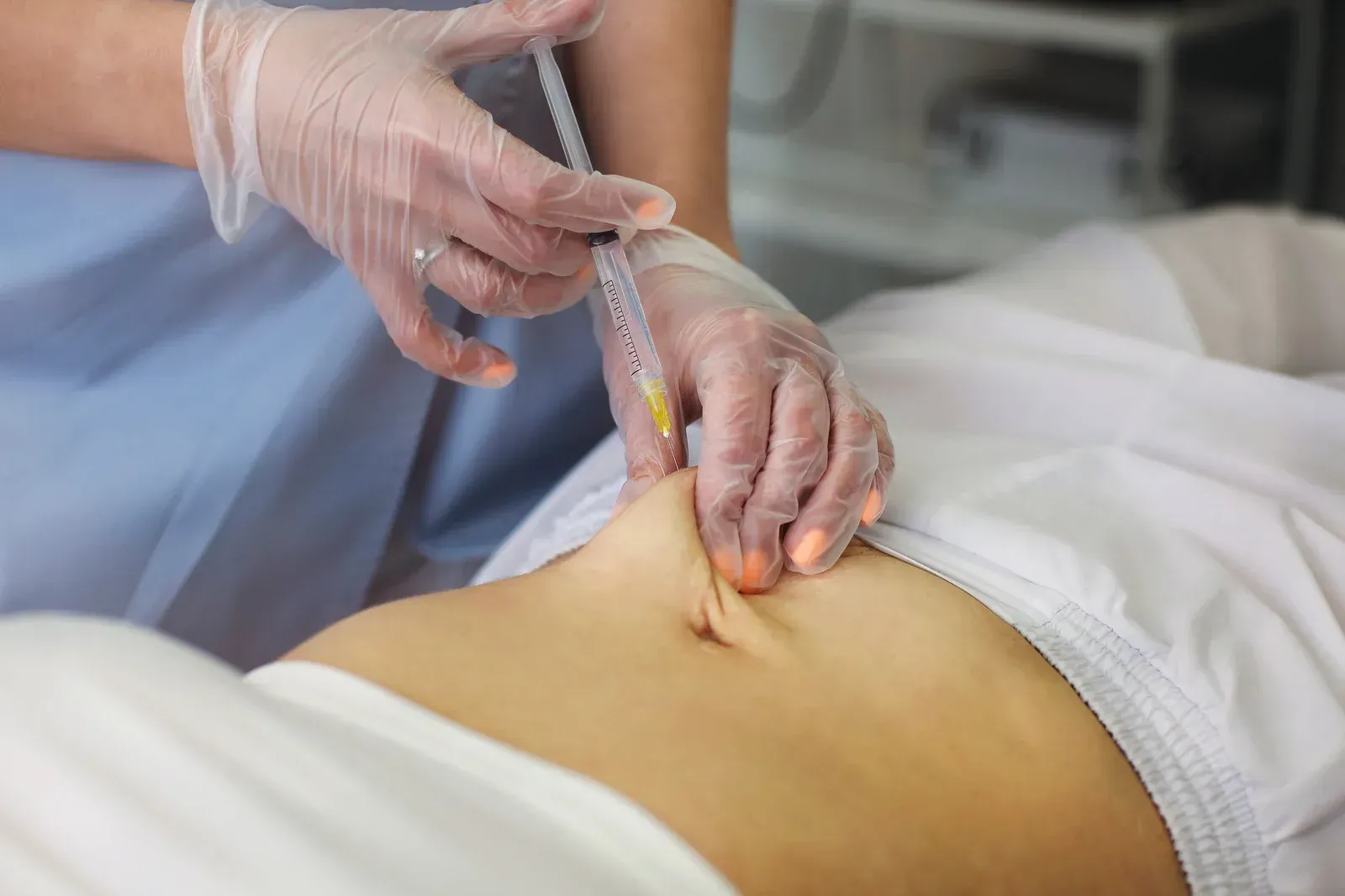 A woman is getting an injection in her stomach.