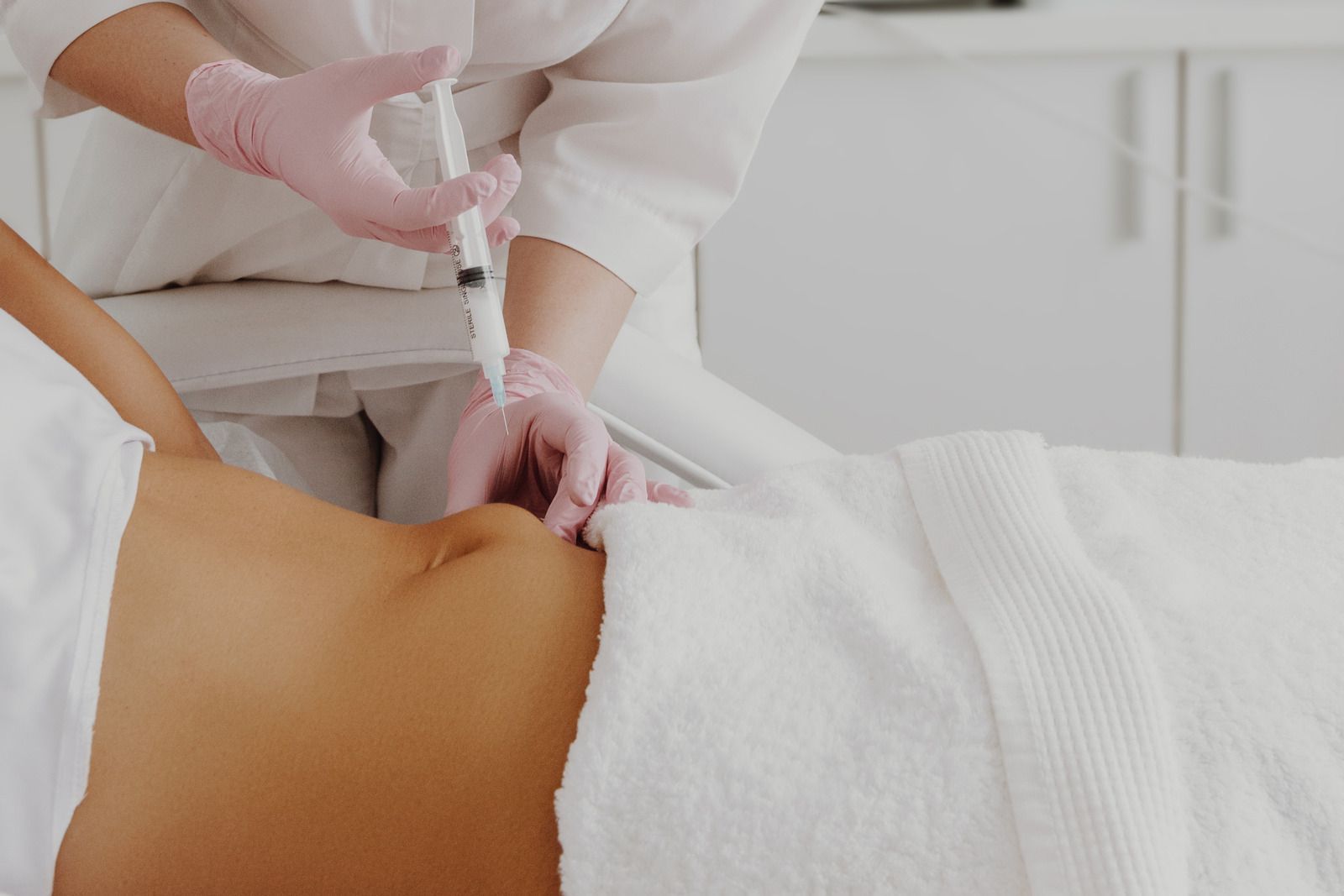 A woman is getting an injection in her stomach.