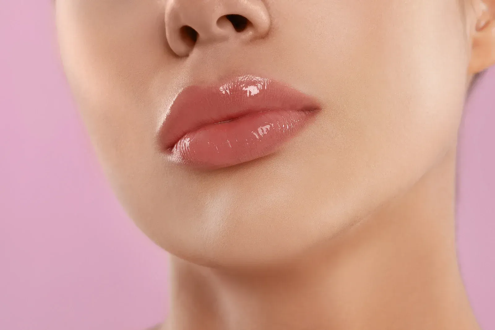 A close up of a woman 's lips on a pink background.