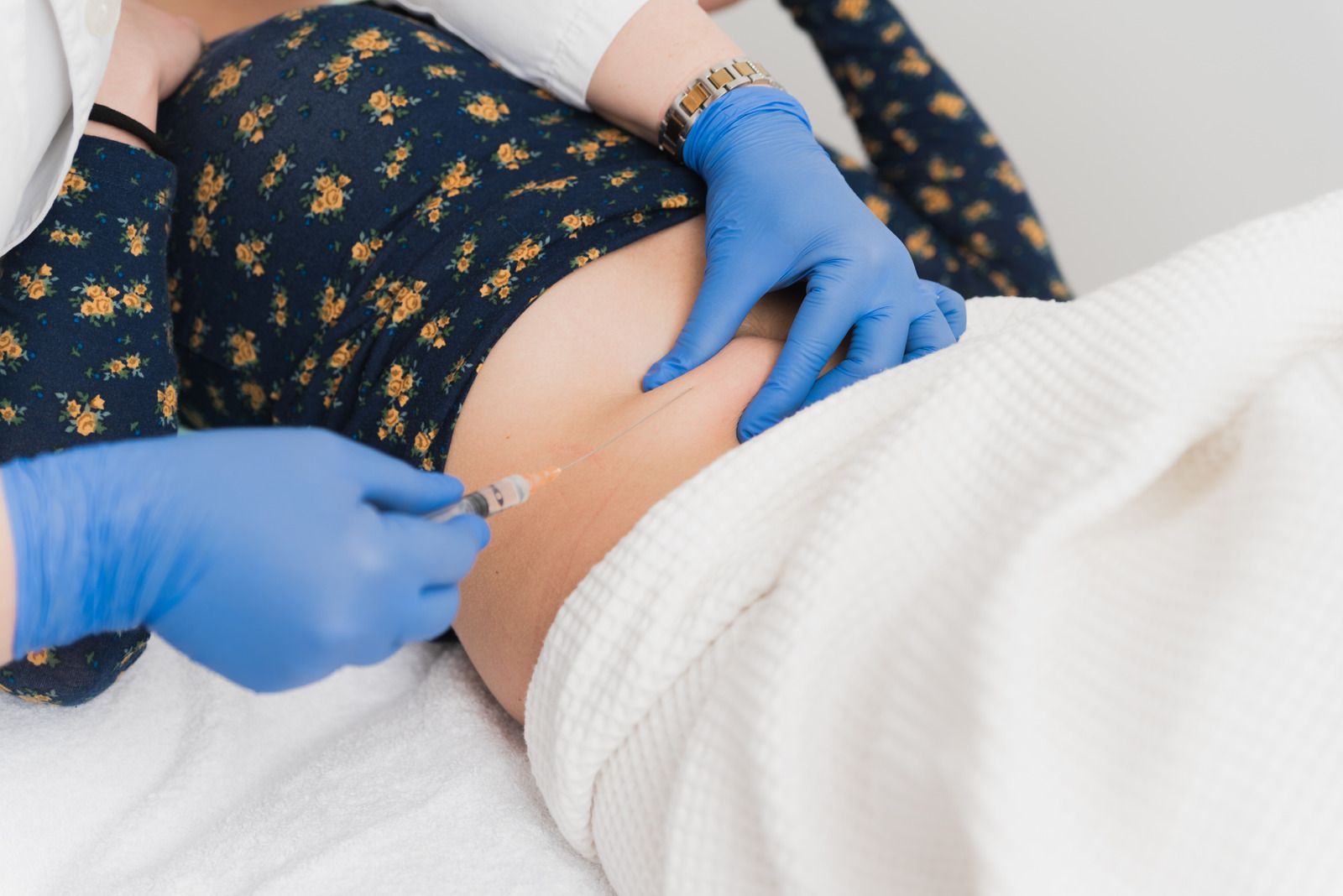 A woman is getting an injection in her stomach.