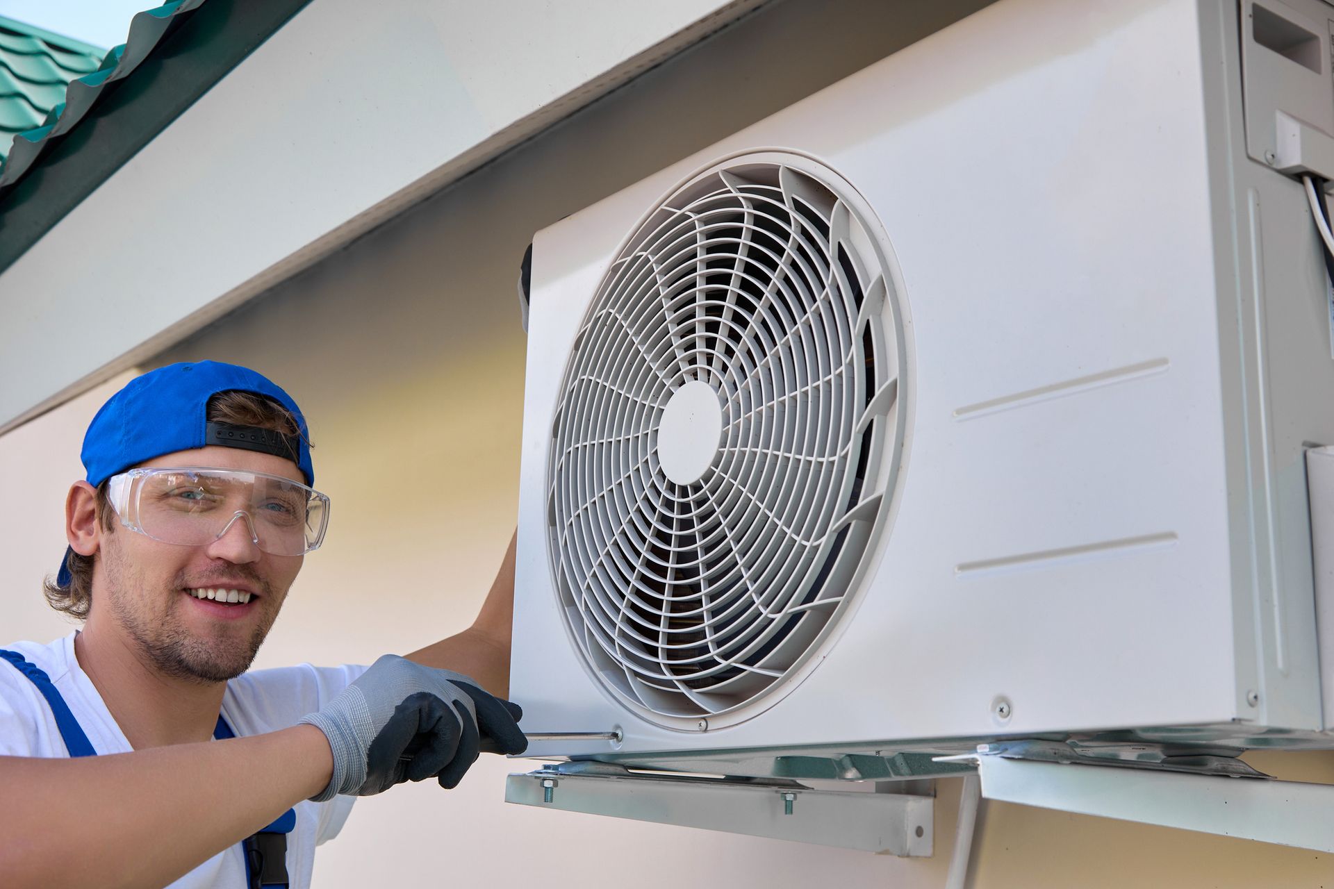 Split system installation by a smiling technician using a screwdriver. Split system installation by a smiling technician using a screwdriver.