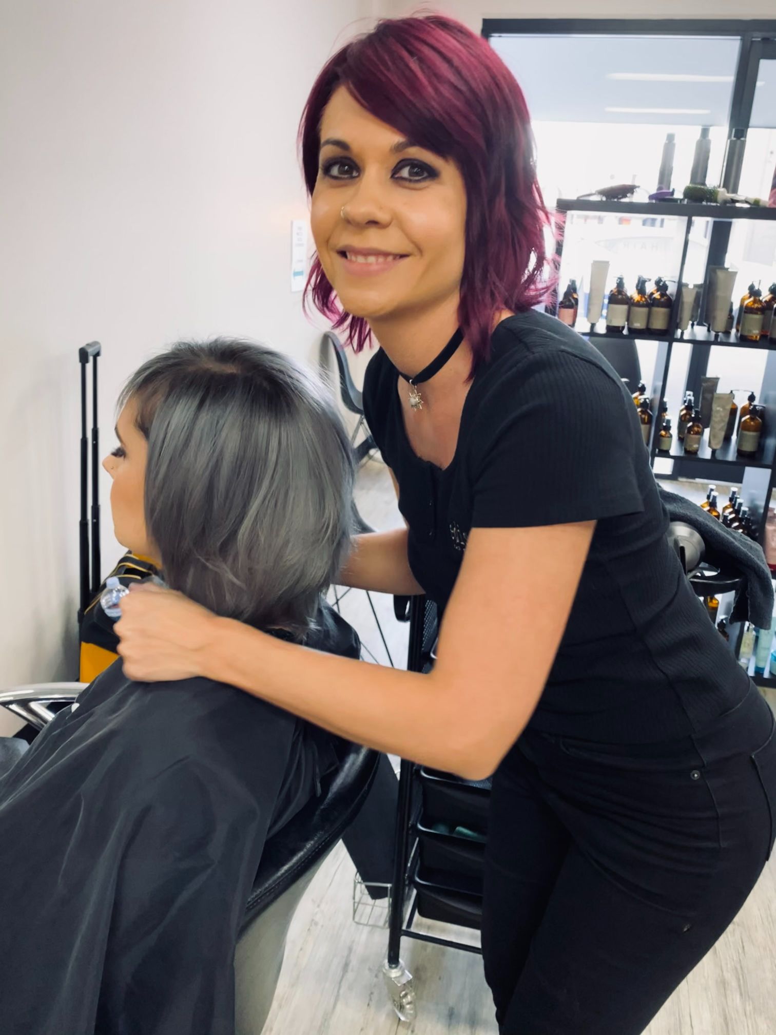 A woman with red hair is cutting a woman 's hair in a salon - Hairdresser in Mackay, QLD