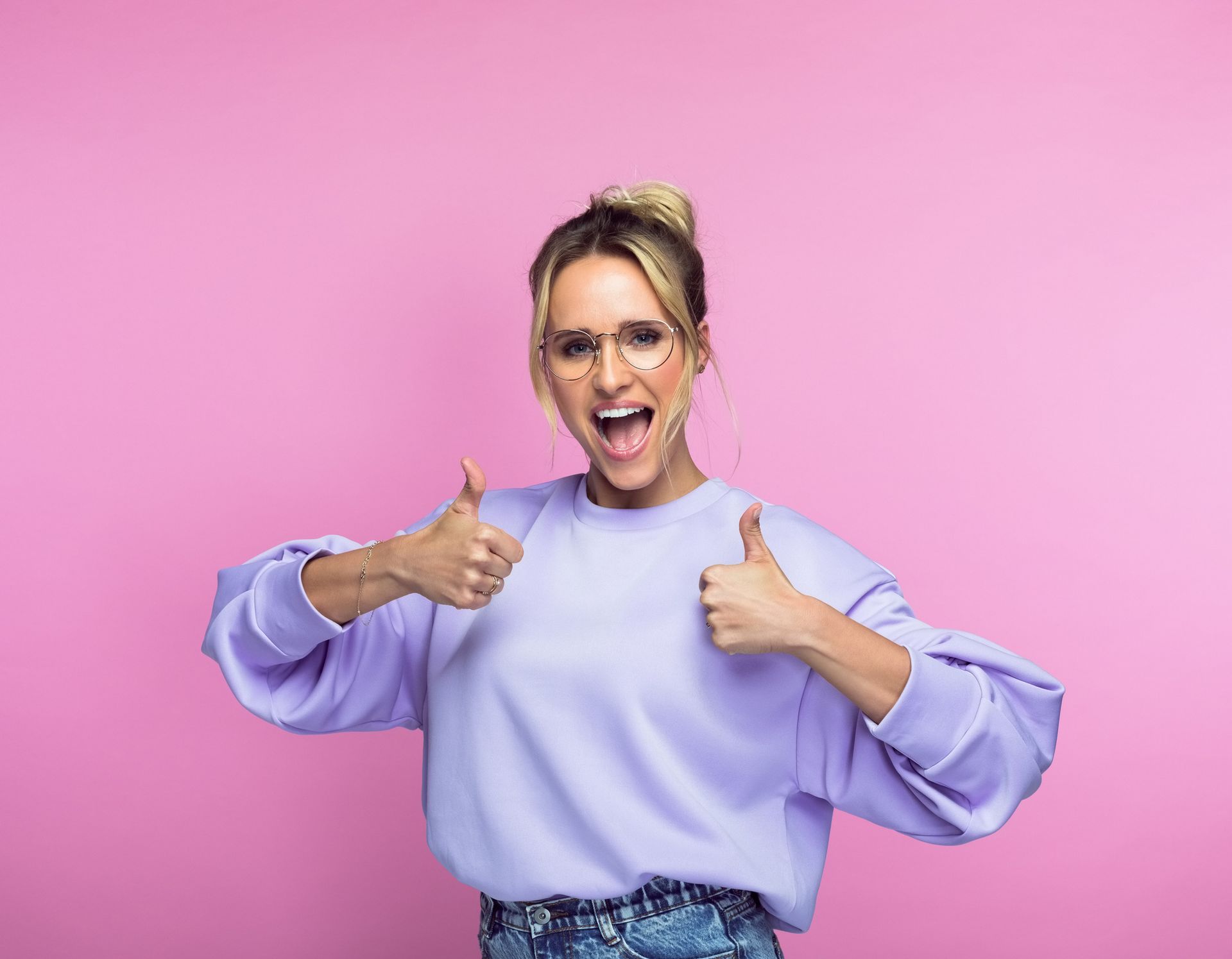 a woman with a light purple shirt and both of her thumbs up