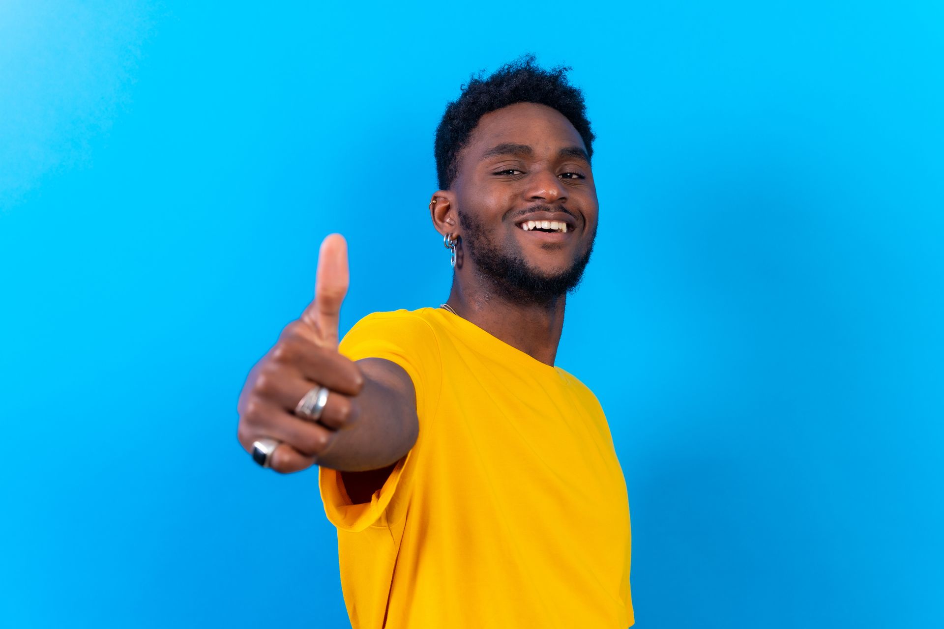 a man in a yellow shirt with his thumbs up