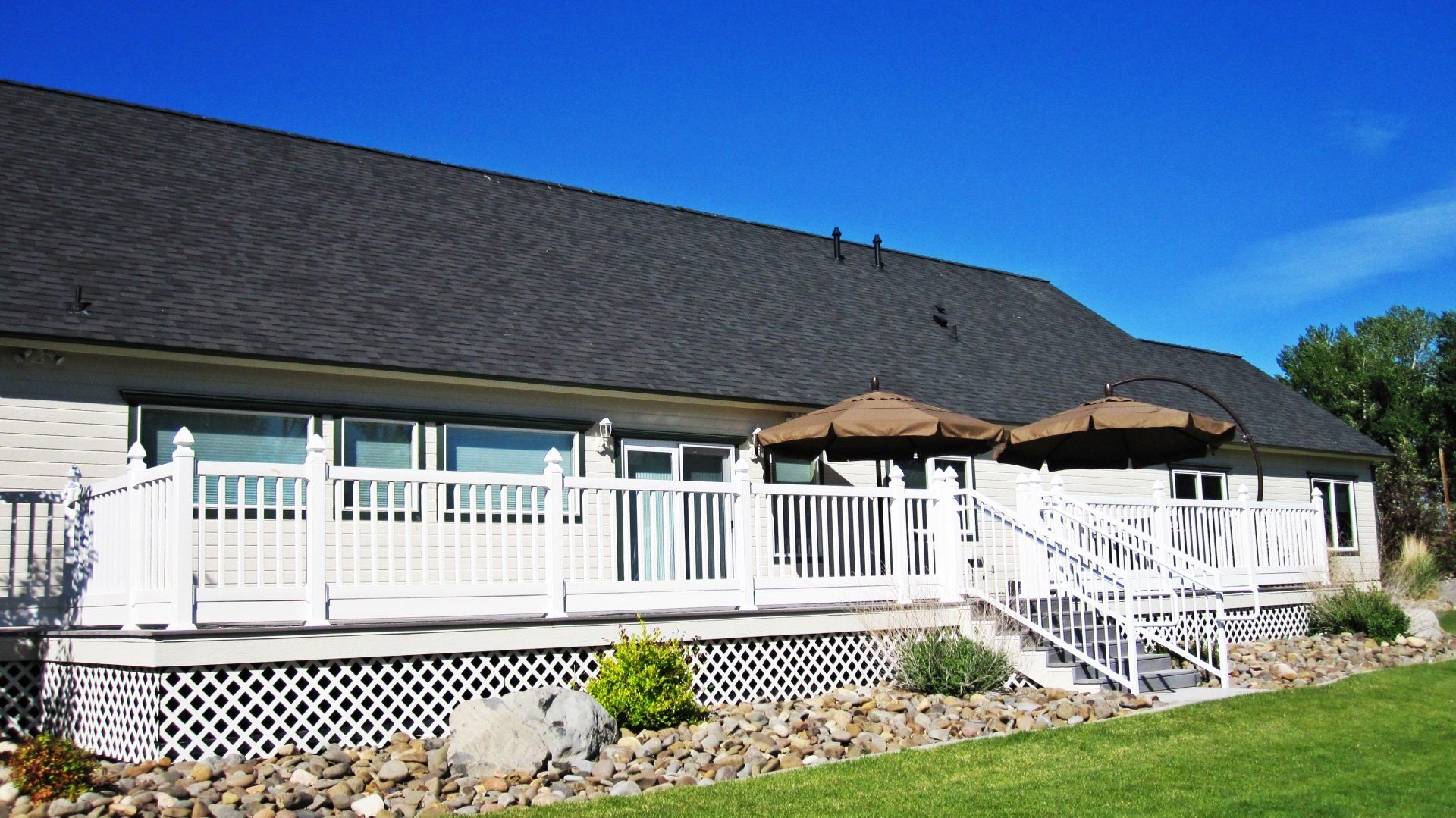 The back of a house with a large deck and stairs leading to it.
